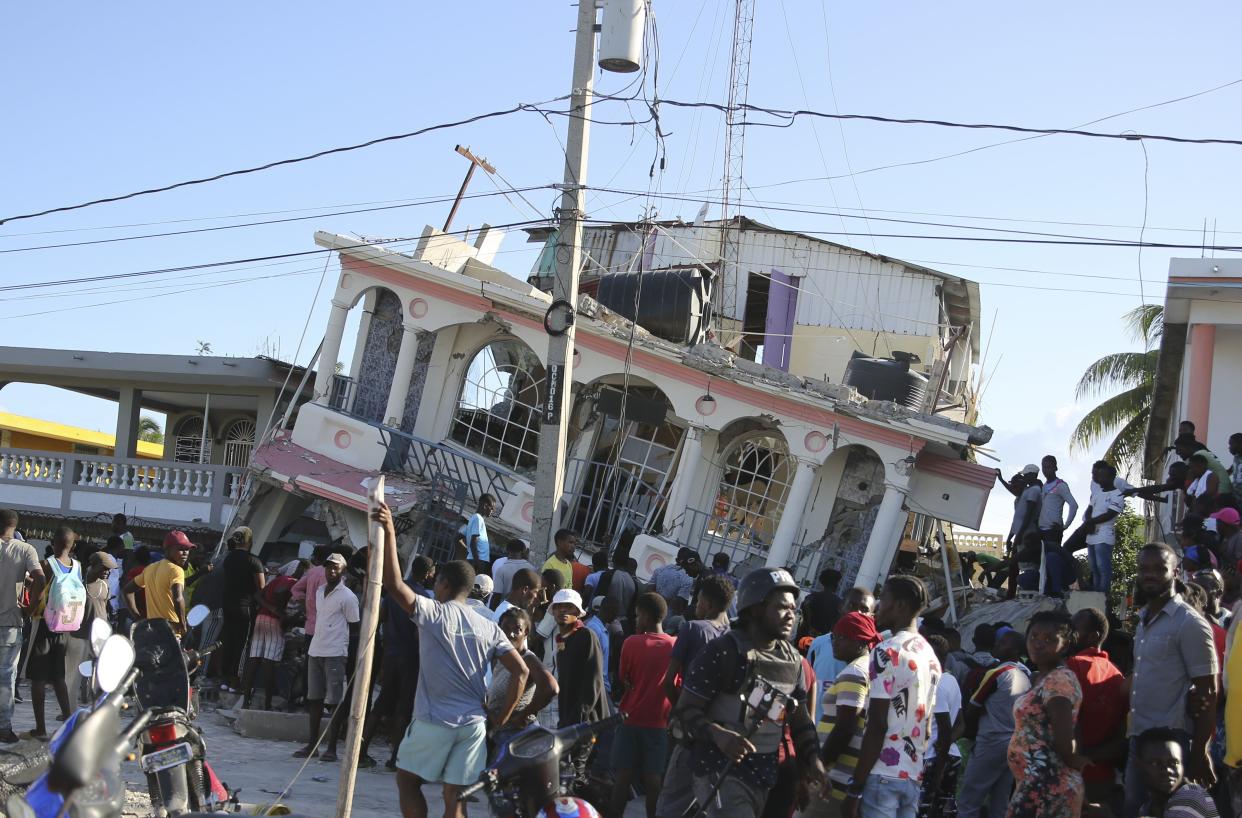 People gather outside the Petit Pas Hotel, destroyed by the earthquake in Les Cayes, Haiti, Saturday, Aug. 14, 2021. A 7.2 magnitude earthquake struck Haiti on Saturday, with the epicenter about 125 kilometers (78 miles) west of the capital of Port-au-Prince, the US Geological Survey said. 
