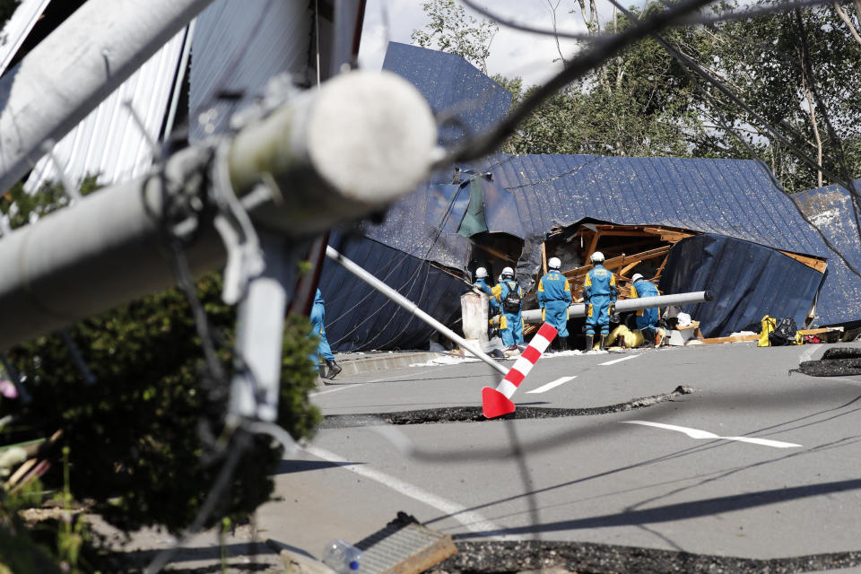 Police search missing persons around buildings destroyed by a landslide triggered by an earthquake in Atsuma town, Hokkaido, northern Japan, Thursday, Sept. 6, 2018. Several people were reported missing in the nearby the town, where a massive landslide engulfed homes in an avalanche of soil, rocks and timber. (Masanori Takei/Kyodo News via AP)