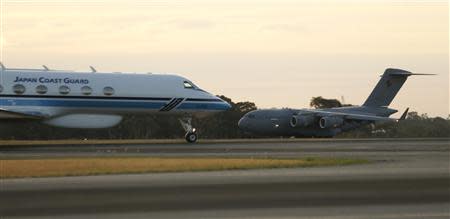 A Japan Coast Guard taxis past an Australian Air Force C-17 Globemaster as it lands at the RAAF Base Pearce near Perth, March 28, 2014. REUTERS/Jason Reed