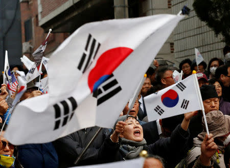 Supporters of South Korea's ousted leader Park Geun-hye wave the national flags as they wait for her arrival outside her private home in Seoul, South Korea, March 12, 2017. REUTERS/Kim Kyung-Hoon