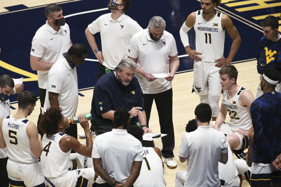 West Virginia coach Bob Huggins, center, speaks with players during the second half of an NCAA college basketball game against Oklahoma, Saturday, Feb. 13, 2021, in Morgantown, W.Va. (AP Photo/Kathleen Batten)