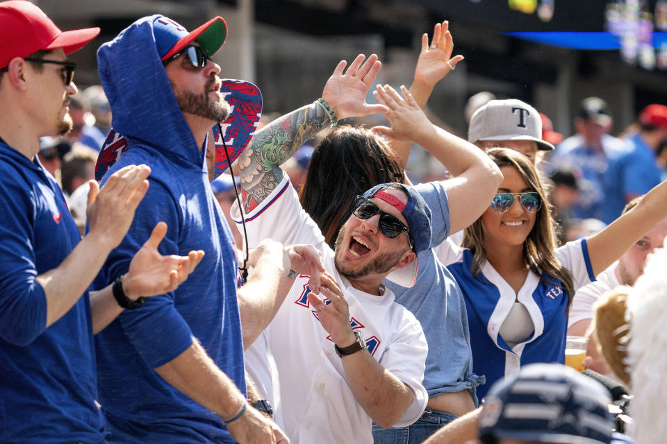 Image: A Texas Rangers fan celebrates with friends during the fourth inning of a baseball game against the Toronto Blue Jays on April 5, 2021, in Arlington, Texas. (Jeffrey McWhorter / AP)