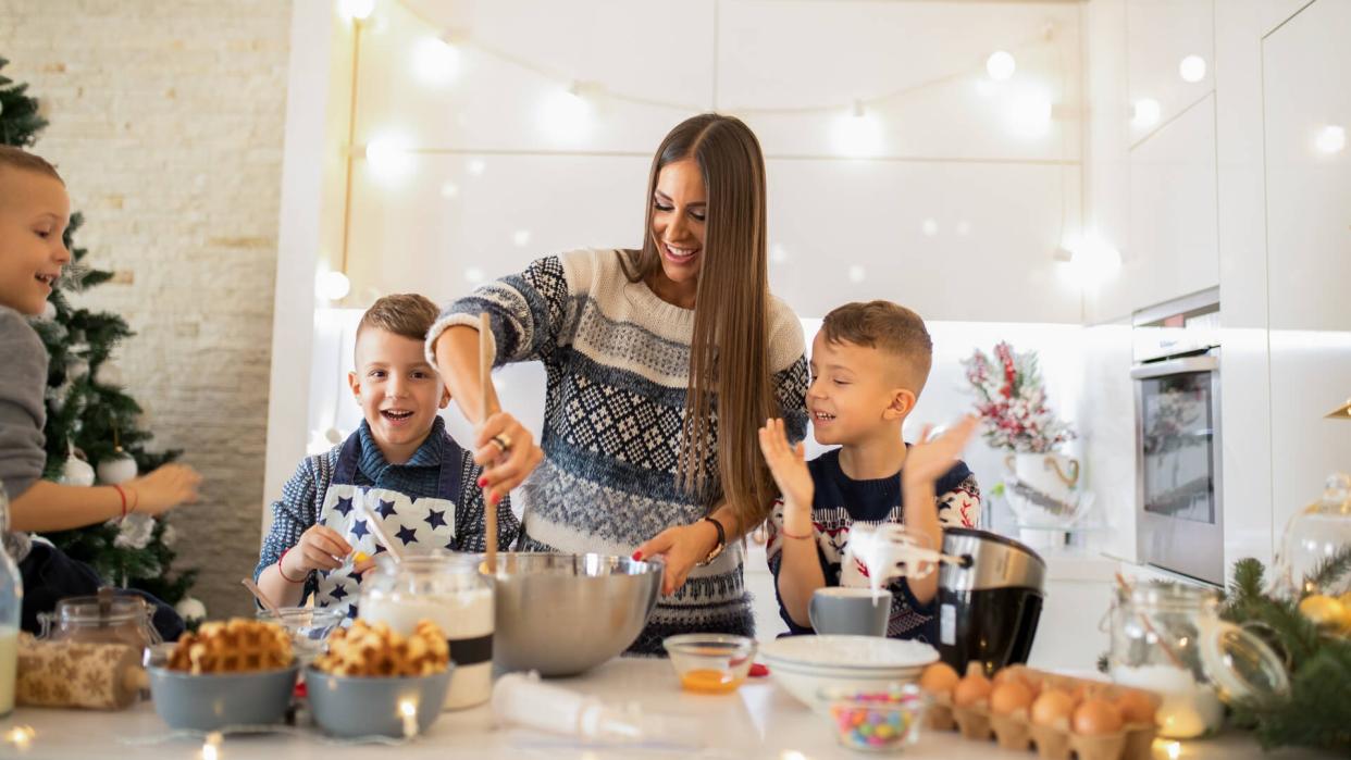 Mother with three sons making Christmas sweets.