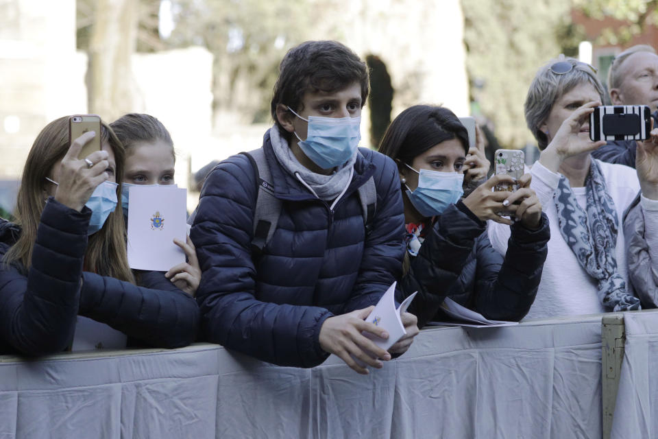 Faithful wear surgical masks as they wait for the arrival of Pope Francis outside the Santa Sabina Basilica on the occasion of the Ash Wednesday Mass opening Lent, the forty-day period of abstinence and deprivation for Christians before Holy Week and Easter, in Rome, Wednesday, Feb. 26, 2020. Pope Francis celebrated the Ash Wednesday ritual kicking off the Catholic Church's Lenten season in traditional fashion, while other Masses in northern Italy were canceled over fears of the new coronavirus. (AP Photo/Gregorio Borgia)