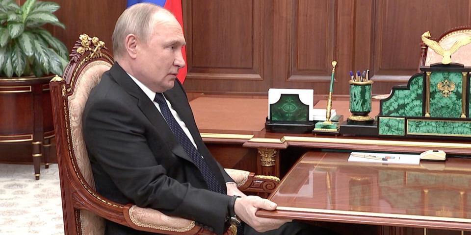 President Vladimir Putin grips a table in a meeting with his defense secretary on April 21, 2022