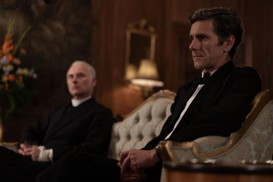 mark bonnar and mathew baynton in murder is easy, both wearing black and sitting on fancy furniture