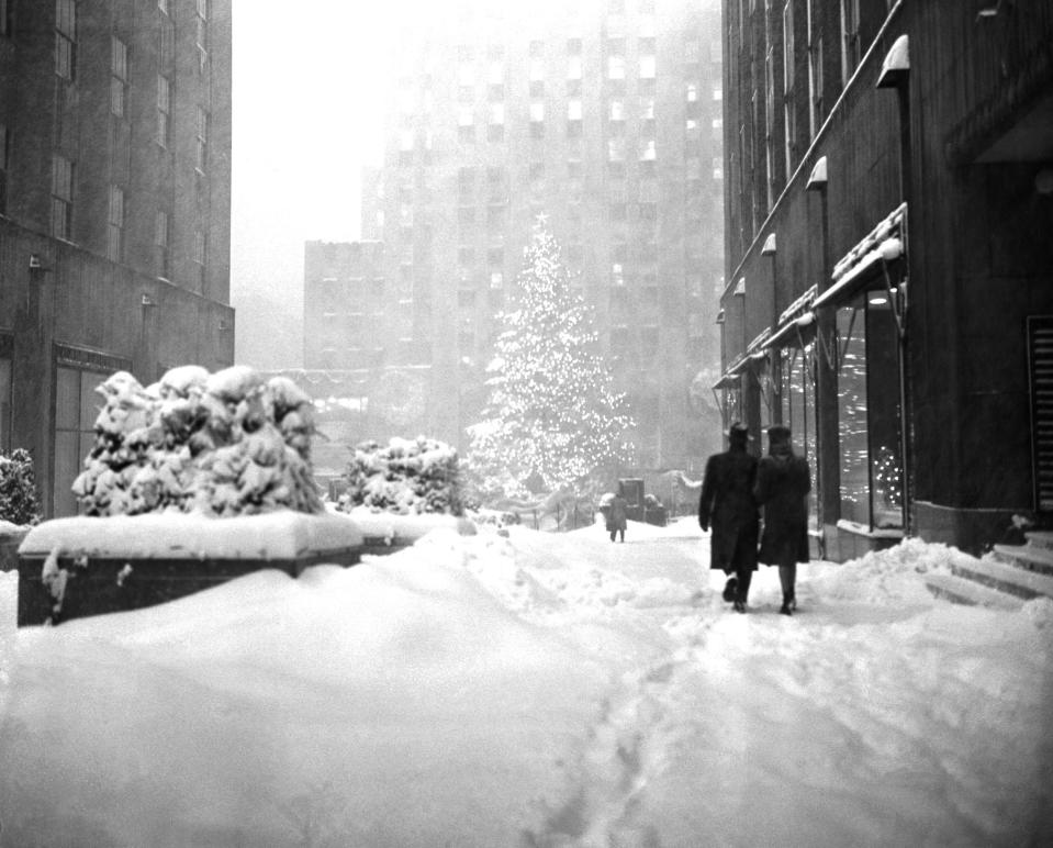 The landmark Christmas tree at New York's Rockefeller Plaza stands out Dec. 26, 1947 as a few hardy pedestrians make their way through the snow drifts of one of the heaviest winter storms in years.