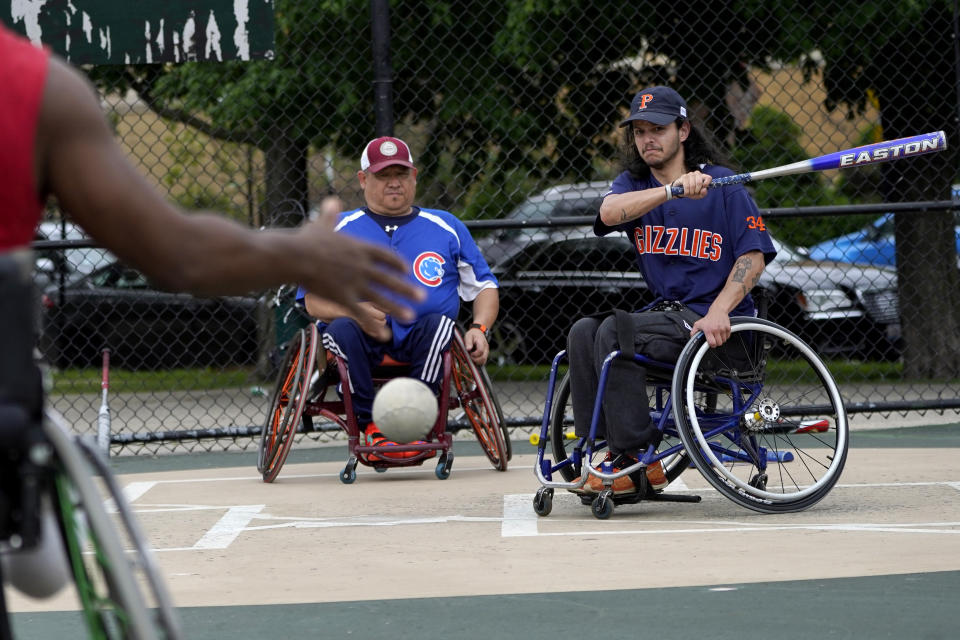 Jonathan Annicks, right, takes batting practice on an adult handicap softball team as team Captain Jorge "Georgie" Alfaro watches Saturday, June 11, 2022, in Chicago. "This is gonna sound cheesy … but people like Johnny provide a beacon to people who are out there – (because he's) doing school, doing work," said Alfaro. (AP Photo/Charles Rex Arbogast)