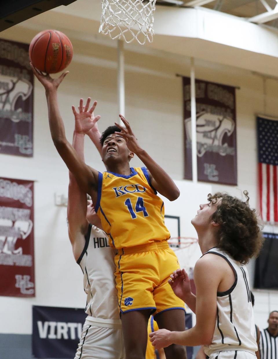 Kentucky Country Day's Cameron Edwards (14) slipped between a couple of Holy Cross defenders to score during the opening round of the Boys LIT at the Holy Cross High School in Louisville, Ky. on Jan. 9, 2023.  KCD won 60-52.