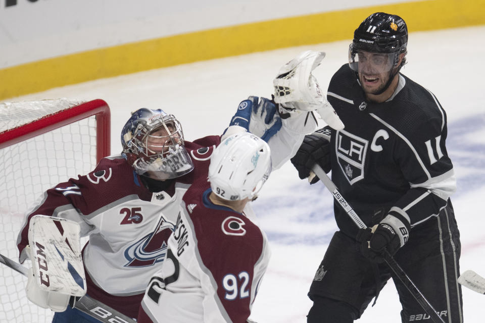 Colorado Avalanche goaltender Philipp Grubauer, left, catches the puck flying in the air between Los Angeles Kings center Anze Kopitar, right, and Avalanche left wing Gabriel Landeskog during the first period of an NHL hockey game Tuesday, Jan. 19, 2021, in Los Angeles. (AP Photo/Kyusung Gong)