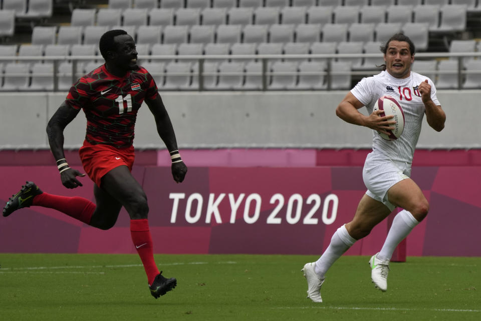 Madison Hughes of the U.S. is chased by Kenya's Collins Injera as he runs down the pitch to score a try, in their men's rugby sevens match at the 2020 Summer Olympics, Monday, July 26, 2021 in Tokyo, Japan. (AP Photo/Shuji Kajiyama)