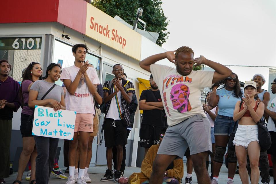 A person dancing in front of a crowd next to a building.