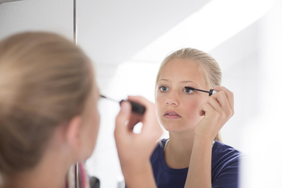 Twelve-year-old girl applying mascara in front of a mirror. Photo: Photo by Ute Grabowsky/Photothek for Getty Image.