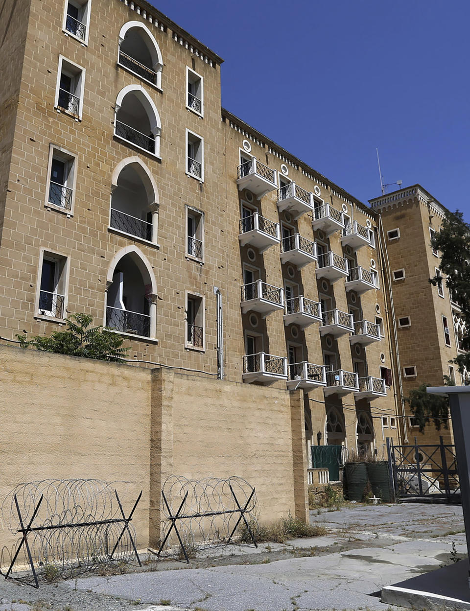 In this Saturday, May 18, 2019 photo, the Ledra Palace Hotel is seen with the holes from bullets during the coup and the Turkish invasion, inside the U.N. buffer zone in the divided capital Nicosia, Cyprus. This grand hotel still manages to hold onto a flicker of its old majesty despite the mortal shell craters and bullet holes scarring its sandstone facade. Amid war in the summer of 1974 that cleaved Cyprus along ethnic lines, United Nations peacekeepers took over the Ledra Palace Hotel and instantly turned it into an emblem of the east Mediterranean island nation's division. (AP Photo/Petros Karadjias)