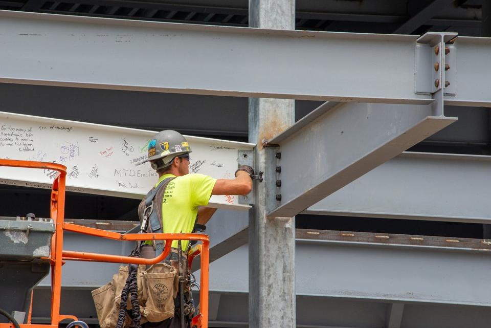 A construction worker fastens the final steel beam for Hagerstown's new field house into place.
