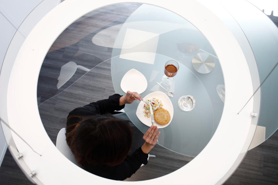 A woman poses under a Plex'Eat prototype plexiglas bubble by designer Christophe Gernigon which surrounds diners to protect them from the novel coronavirus during a presentation in Cormeilles-en-Parisis, near Paris, as restaurants in France prepare to re-open post-lockdown, May 20, 2020. Picture taken May 20, 2020.  REUTERS/Benoit Tessier