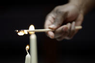 In this Jan. 17, 2020, photo Corey Caver lights candles before the Friday Shabbat Service at KAM Isaiah Israel in Chicago. On the eve of the day set aside to honor an African American who strove against hate and preached racial and social justice, some worry the nation is becoming more divided. (AP Photo/Nam Y. Huh)