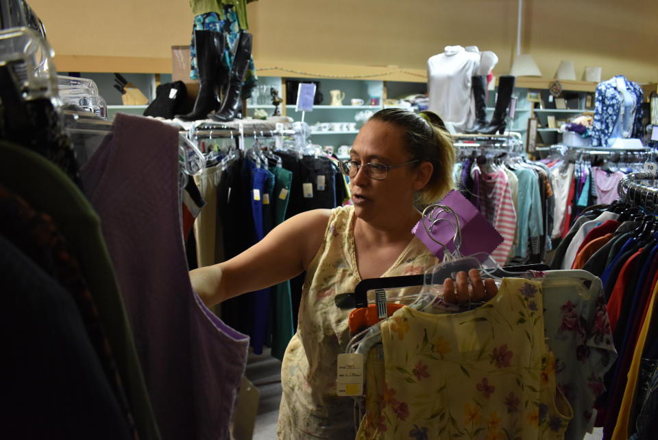 Shannon Thompson looks through clothing items at the Northern Treasure thrift store on Monday, April 27, 2020 in Roundup, Mont. As shutdowns are eased in parts of America, some of the quickest to reopen are rural states. (AP Photo/Matthew Brown)