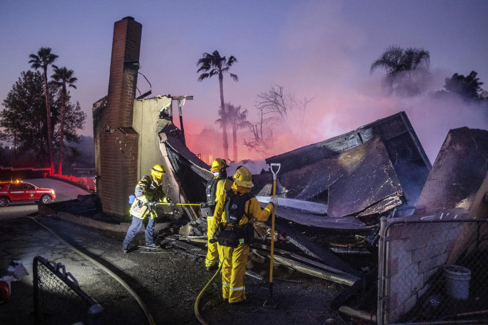 Firefighters mop up at a leveled home as the Hillside Fire burns in San Bernardino, Calif., on Thursday, Oct. 31, 2019. The blaze, which ignited during red flag fire danger warnings, destroyed multiple residences. (AP Photo/Noah Berger)