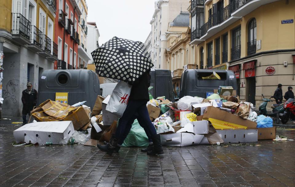 A pedestrian walks next to garbage strewn on the pavement during a strike by street cleaners in Madrid