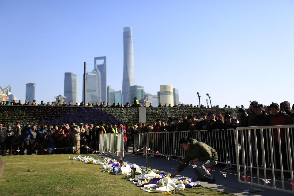 People lay down flowers during a memorial ceremony in memory of people who were killed in a stampede incident during a New Year's celebration on the Bund, in Shanghai