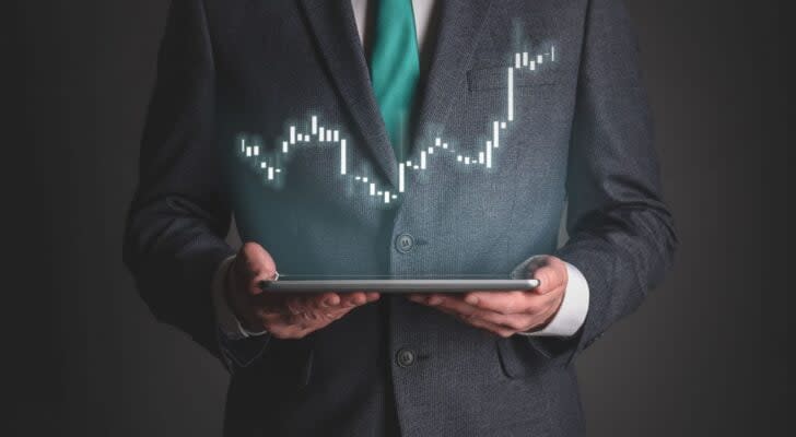 man in suit holding a tablet with graphic above showing oversold stocks to buy