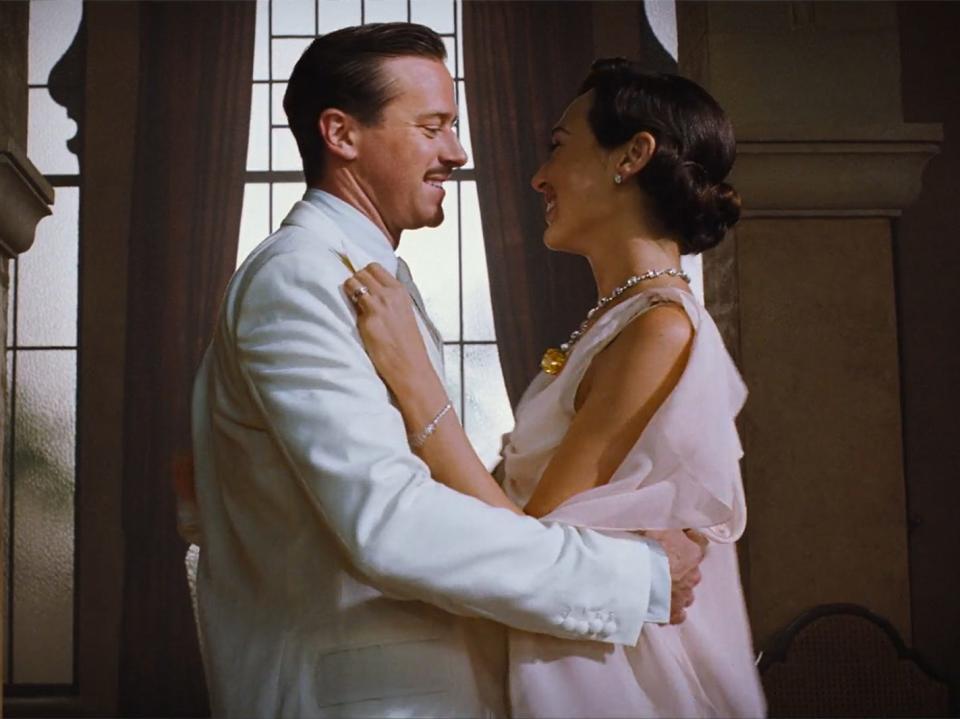 Simon Doyle, in a white suit, and Linnet Ridgeway, in a pink dress, dance together in this still from "Death on the Nile."