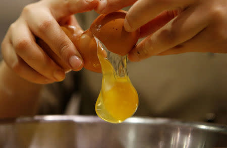 A pastry chef breaks an egg as she prepares to bake a cake at a bakery in Seoul, South Korea, December 22, 2016. REUTERS/Kim Hong-Ji