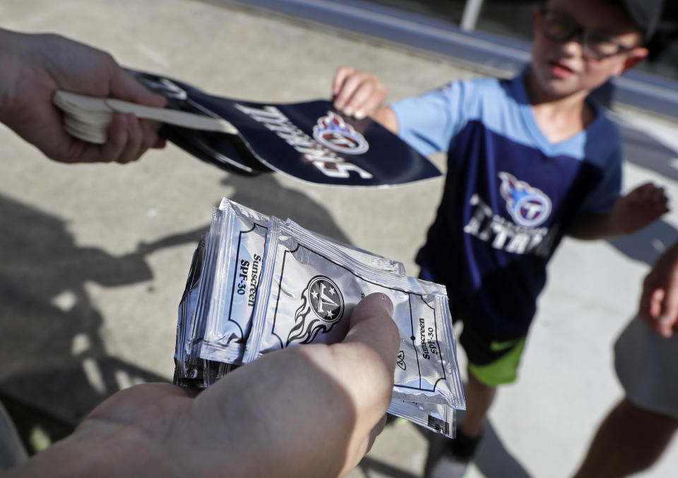 Packets of sunscreen along with paper fans are offered to spectators during Tennessee Titans NFL football training camp Tuesday, Aug. 7, 2018, in Nashville, Tenn. (AP Photo/Mark Humphrey)