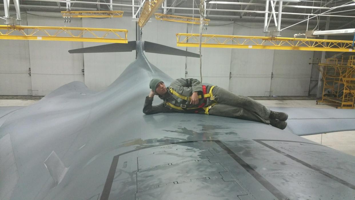 Man laying on airplane fuselage in flightsuide