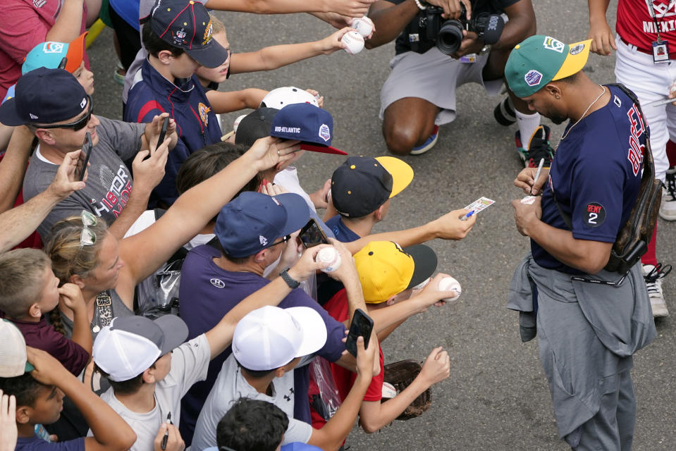 Boston Red Sox's Xander Bogaerts, right, gives autographs as his team arrived at the Little League World Series tournament in South Williamsport, Pa., Sunday, Aug. 21, 2022. (AP Photo/Tom E. Puskar)
