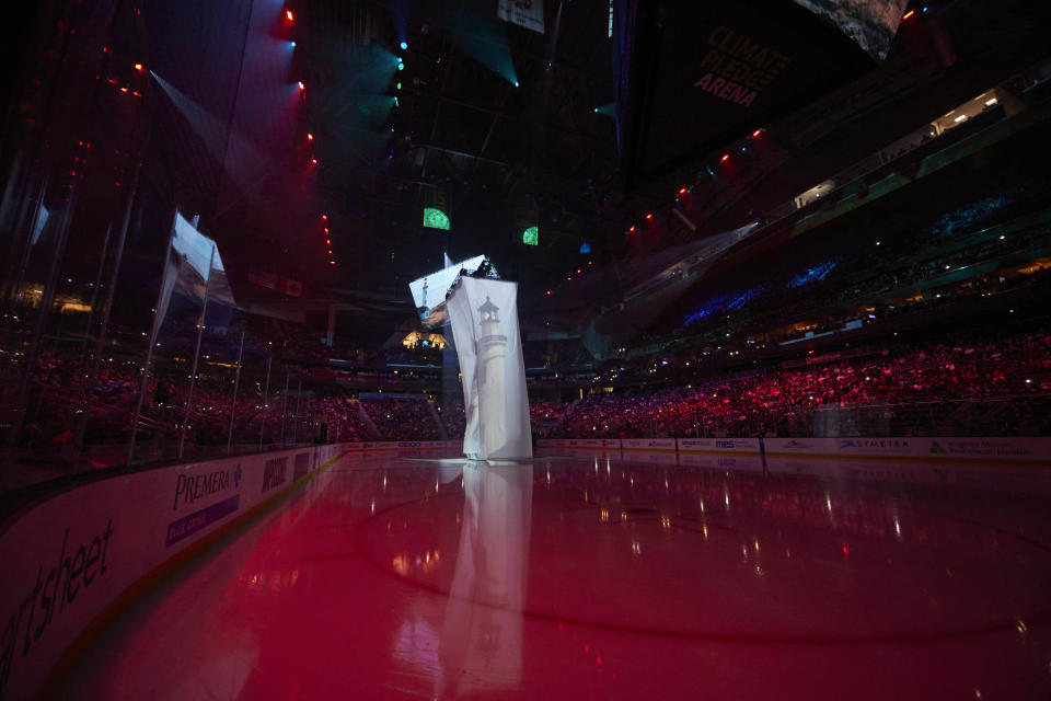 An image of a lighthouse is projected during pregame introductions of the Seattle Kraken NHL hockey team before a game against the St. Louis blues in Seattle, Wednesday, Oct. 19, 2022. With Hollywood filmmaker Jerry Bruckheimer as part of the ownership group, the Seattle Kraken were always going to have a big cinematic element to any video production the team produced. (AP Photo/John Froschauer)