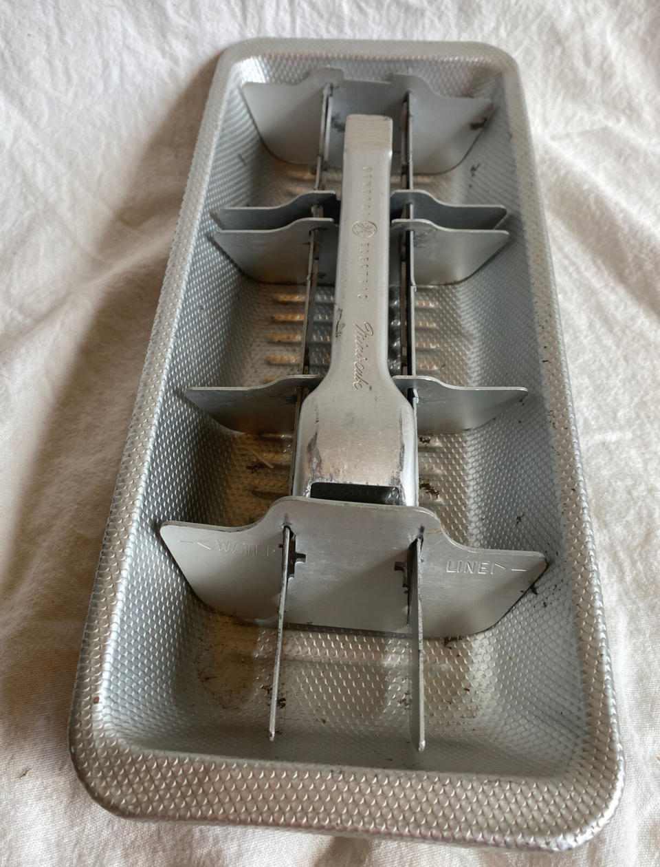 An old metal, rigid ice tray with hand lever