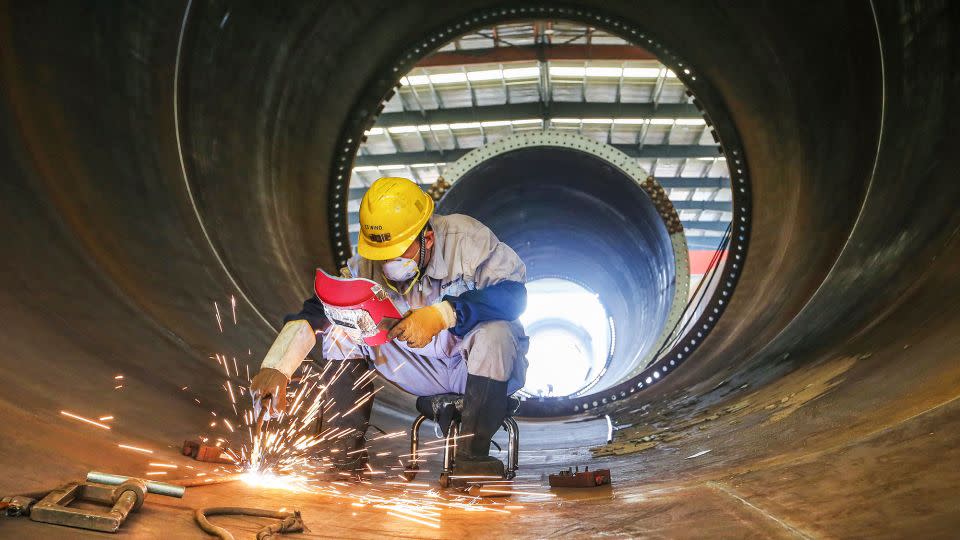 An employee works on a wind turbine tower at a factory in Lianyungang, China, in October 2023. - STR/AFP/Getty Images