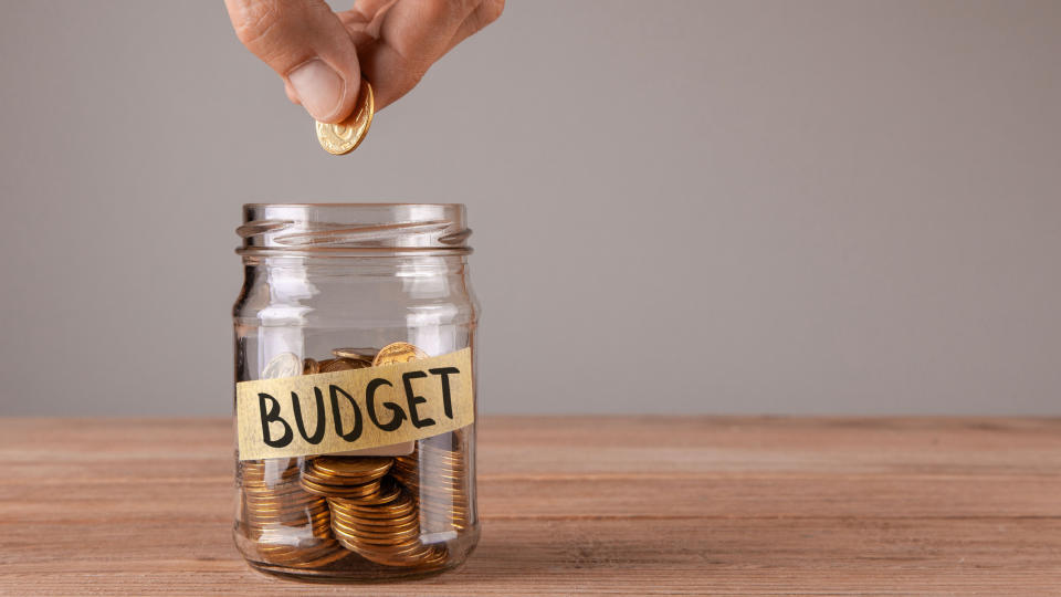 someone putting a coin into a jar labeled budget