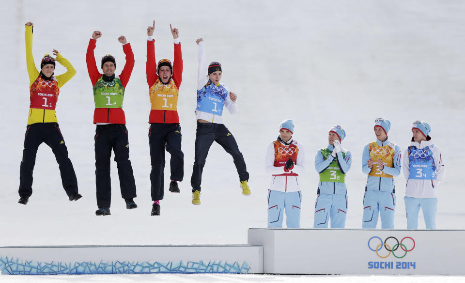 Germany's team celebrate winning the silver as Norway's gold medal winners applaud, during the flower ceremony of the Nordic combined Gundersen large hill team competition at the 2014 Winter Olympics, Feb. 20, 2014, in Krasnaya Polyana, Russia.