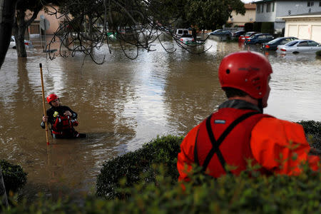 A firefighter with the San Jose Fire Department walks in a flooded neighborhood after heavy rains overflowed nearby Coyote Creek in San Jose, California. REUTERS/Stephen Lam