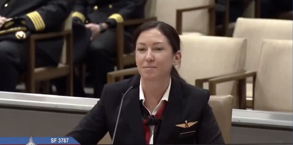 Woman in airline uniform with insignia speaking at a podium