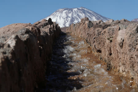 Water flows in an irrigation canal in front of Lascar volcano in the Talabre area at Atacama salt flat in the Atacama desert, Chile, August 16, 2018. REUTERS/Ivan Alvarado