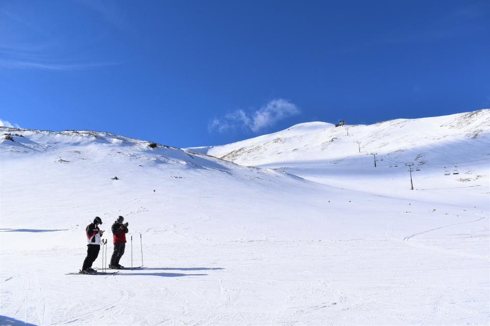 Two skiers check their phones at 12,000 under the peak at Breckenridge on Feb. 2, 2020.