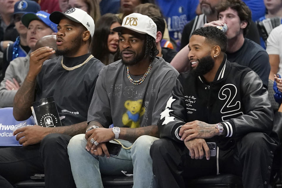 NLF football free agent Odell Beckham Jr., right, sits with Dallas Cowboys Micah parsons, left, and Trevon Diggs during the first half of an NBA basketball game between the Phoenix Suns and Dallas Mavericks in Dallas, Monday, Dec. 5, 2022. (AP Photo/LM Otero)