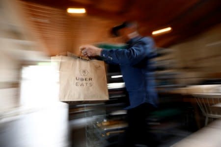 FILE PHOTO - A bag of donuts destined for delivery via Uber Eats is rushed to a driver from a kitchen in Sydney August 12, 2016. Picture taken August 12, 2016. REUTERS/Jason Reed