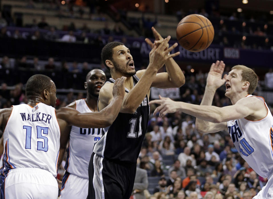 San Antonio Spurs' Jeff Ayres (11) is fouled as he drives between Charlotte Bobcats' Kemba Walker (15) and Cody Zeller (40) during the first half of an NBA basketball game in Charlotte, N.C., Saturday, Feb. 8, 2014. (AP Photo/Chuck Burton)