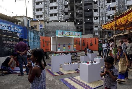 Residents gather around a mobile museum displayed on an improvised handcart in Dharavi, one of Asia's largest slums, in Mumbai, February 18, 2016. REUTERS/Danish Siddiqui