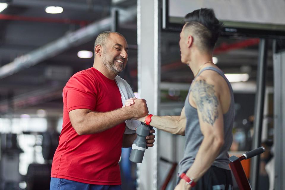 Smiling man greeting fitness instructor at gym