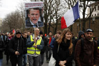 Yellow vests protesters holding a portrait of French President Macron and a French flag march in Paris, Saturday, Dec. 7, 2019. A few thousand yellow vest protesters marched Saturday from the Finance Ministry building on the Seine River through southeast Paris, pushing their year-old demands for economic justice and adding the retirement reform to their list of grievances. (AP Photo/Francois Mori)