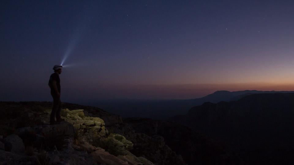 A caver looks out across Carlsbad Caverns National Park at night.