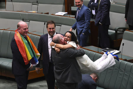 Liberal MP Warren Entsch lifts up Labor MP Linda Burney as they celebrate the passing of the Marriage Amendment Bill in the House of Representatives at Parliament House in Canberra December 7, 2017. AAP/Lukas Coch/via REUTERS