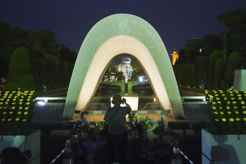 A visitor prays in front of the cenotaph for the atomic bombing victims before the start of a ceremony to mark the 75th anniversary of the U.S. bombing in Hiroshima, western Japan, early Thursday, Aug. 6, 2020. (AP Photo/Eugene Hoshiko)