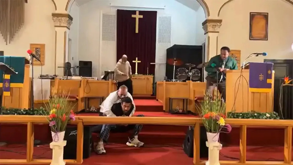 A churchgoer holds the gunman's arms back